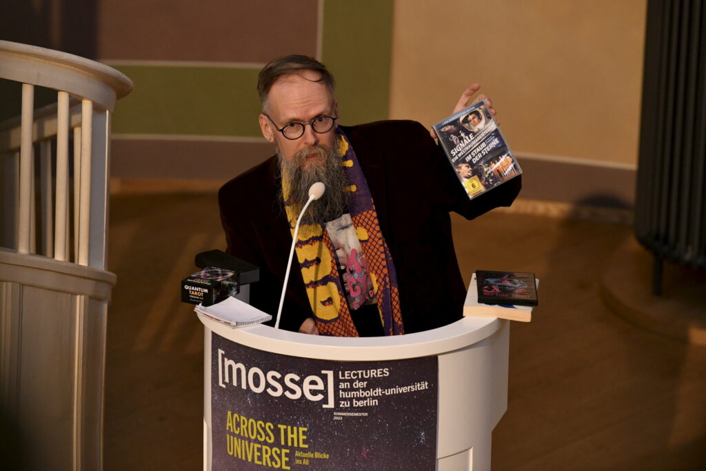 Dietmar Dath zeigt dem Publikum ein DVD-Set mit Science-Fiction Filmen | Mosse Lecture von Dietmar Dath | © Niels Leiser für Mosse Lectures
